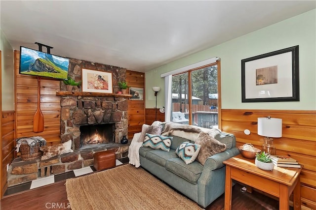 living room featuring wooden walls, wood-type flooring, and a fireplace