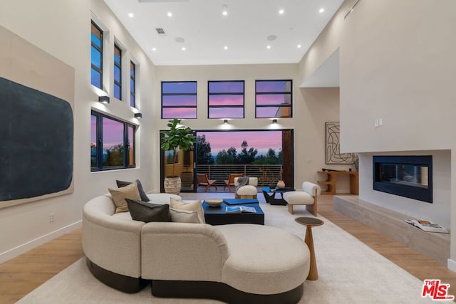 living room featuring a fireplace, light hardwood / wood-style floors, and a high ceiling