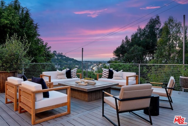 deck at dusk featuring an outdoor living space with a fire pit