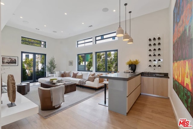 living room with a towering ceiling, light hardwood / wood-style floors, and french doors