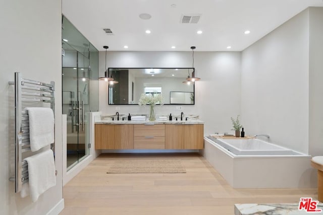 bathroom featuring vanity, hardwood / wood-style floors, radiator, and shower with separate bathtub