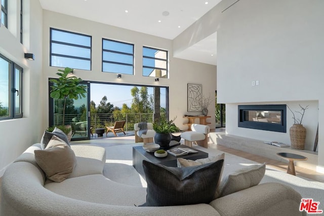 living room featuring wood-type flooring, a fireplace, and a high ceiling