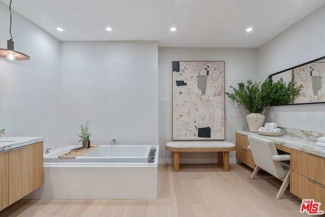 bathroom with vanity, wood-type flooring, and a tub