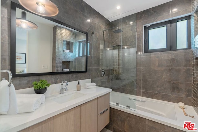 bathroom with vanity, combined bath / shower with glass door, and tile walls