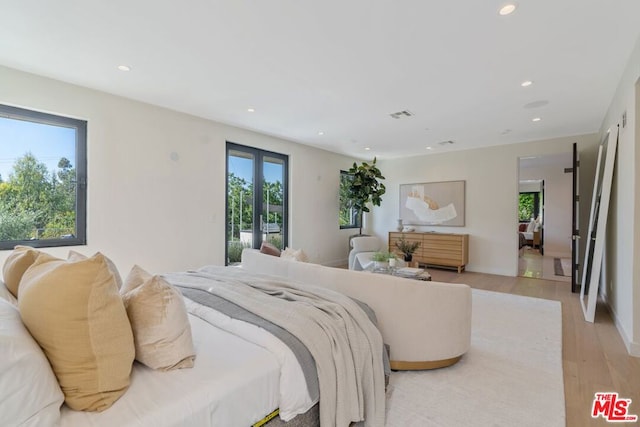 bedroom with access to exterior, light hardwood / wood-style floors, and french doors