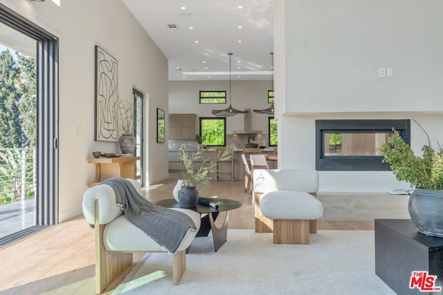 living room with a high ceiling, light wood-type flooring, and a fireplace