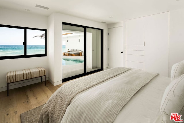 bedroom with a water view and light hardwood / wood-style floors