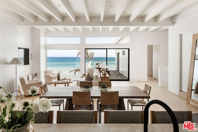 dining room with a water view, beam ceiling, sink, and light hardwood / wood-style flooring