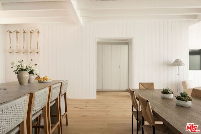 dining area featuring beam ceiling and light hardwood / wood-style flooring