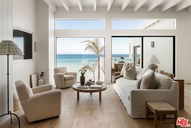 living room featuring a water view, beam ceiling, and light hardwood / wood-style floors