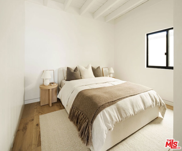 bedroom featuring wood-type flooring and beamed ceiling