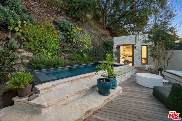 view of swimming pool featuring a wooden deck and an outbuilding