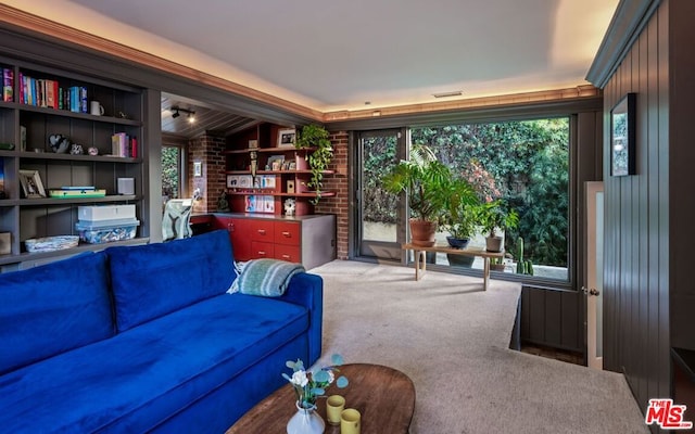 living room with a healthy amount of sunlight, brick wall, and carpet floors