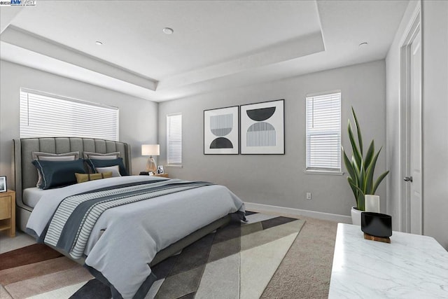 bedroom with a tray ceiling and light colored carpet