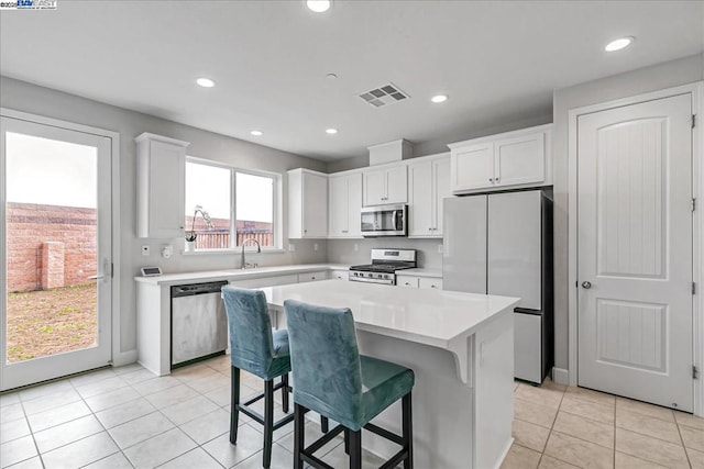 kitchen with white cabinetry, a breakfast bar area, a center island, and appliances with stainless steel finishes