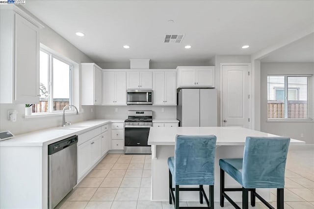 kitchen featuring a kitchen island, appliances with stainless steel finishes, sink, and white cabinets