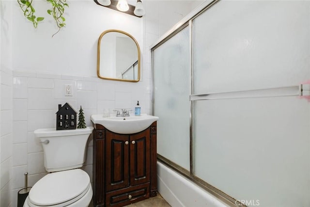 full bathroom with vanity, tile walls, shower / bath combination with glass door, and toilet