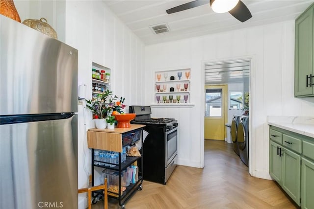 kitchen with green cabinetry, stainless steel appliances, light parquet flooring, and washer and dryer