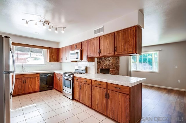 kitchen featuring tasteful backsplash, appliances with stainless steel finishes, a wealth of natural light, and kitchen peninsula