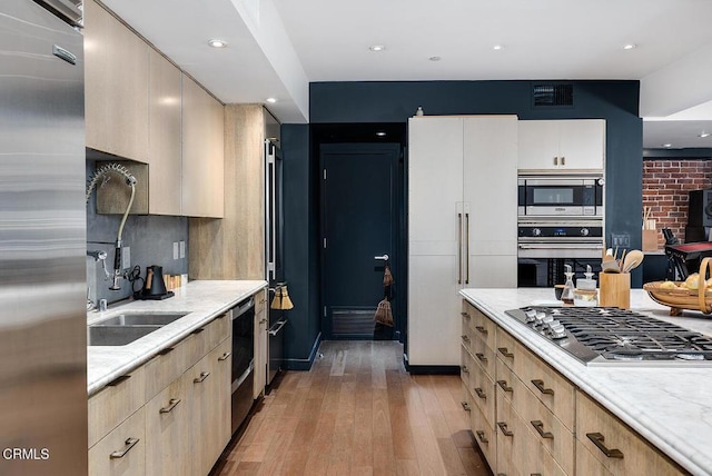 kitchen with stainless steel appliances, light brown cabinetry, and light wood-type flooring