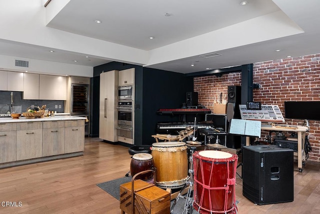 kitchen featuring light hardwood / wood-style flooring, stainless steel appliances, a center island, and brick wall