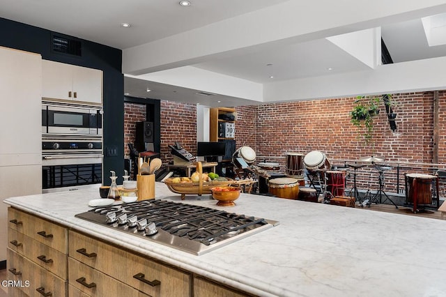 kitchen featuring white cabinetry, brick wall, and appliances with stainless steel finishes