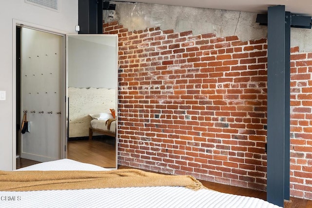 unfurnished bedroom with wood-type flooring, a closet, and brick wall