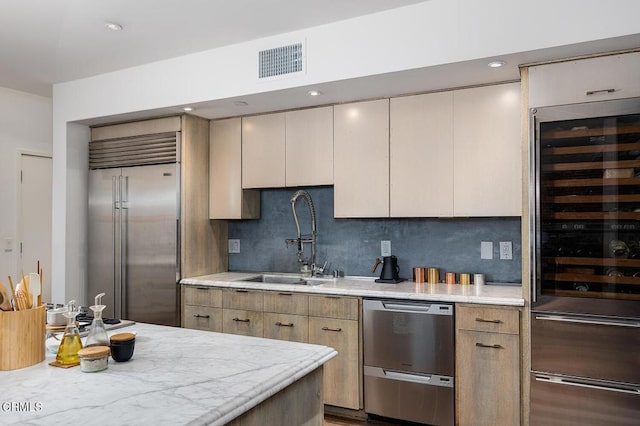 kitchen featuring stainless steel appliances, sink, wine cooler, and backsplash