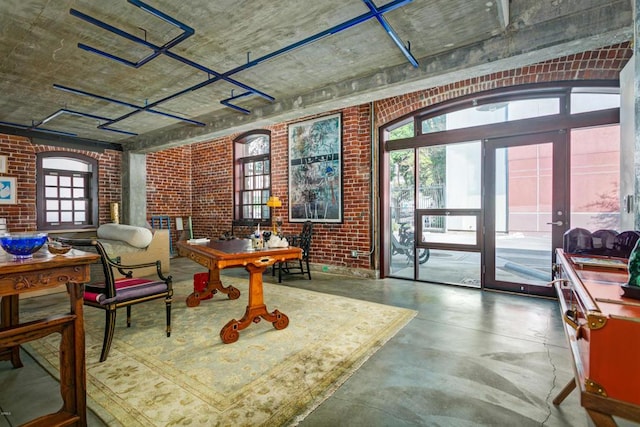 sitting room with concrete flooring, a healthy amount of sunlight, and brick wall