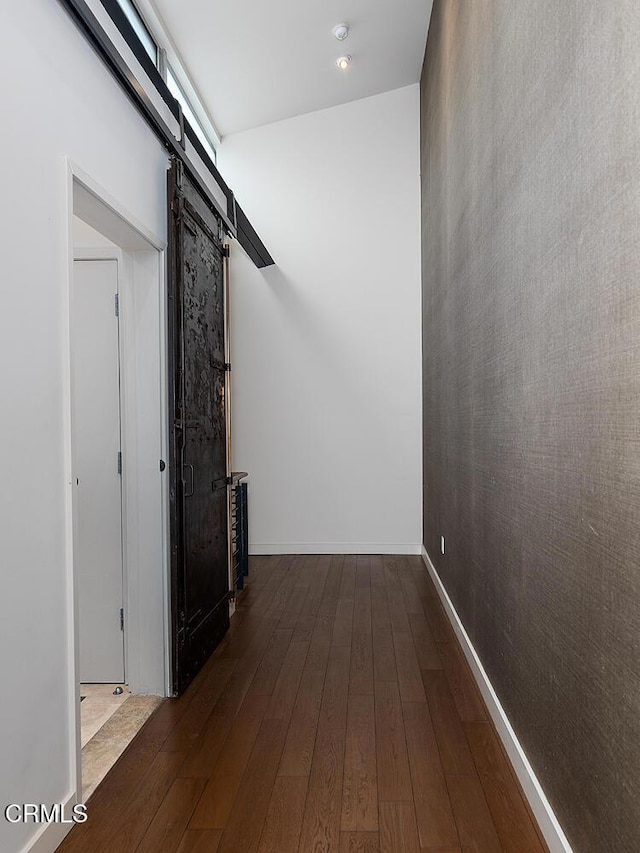 hallway with dark hardwood / wood-style floors and a barn door