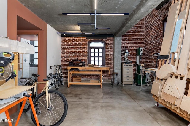 misc room featuring brick wall, a workshop area, and concrete floors