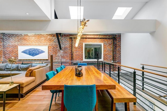 dining area with light hardwood / wood-style floors, a high ceiling, and brick wall