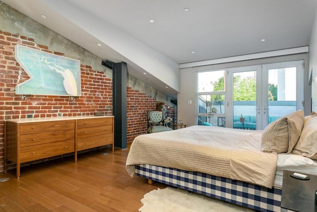 bedroom featuring french doors, brick wall, access to exterior, and hardwood / wood-style floors