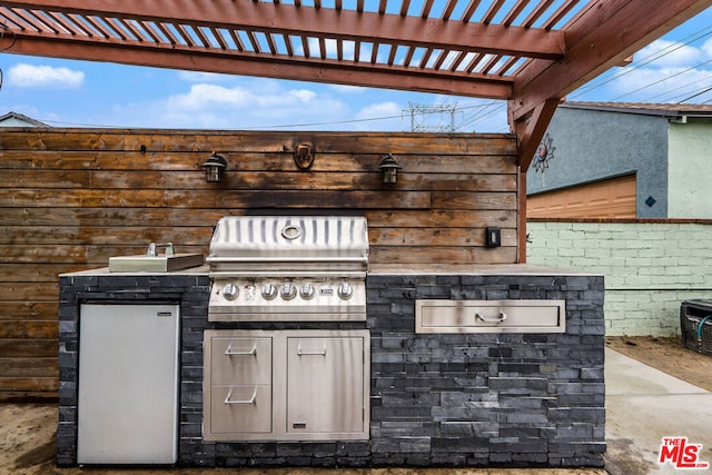 view of patio / terrace with a grill, a pergola, and an outdoor kitchen