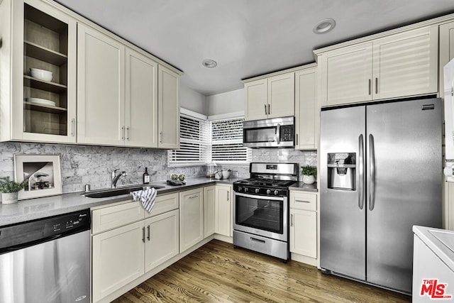 kitchen with sink, appliances with stainless steel finishes, dark hardwood / wood-style flooring, decorative backsplash, and cream cabinetry