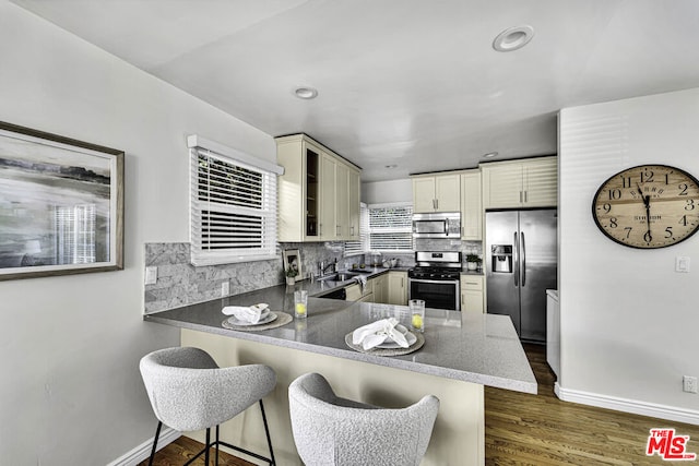 kitchen featuring appliances with stainless steel finishes, a breakfast bar area, backsplash, and kitchen peninsula