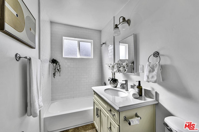 full bathroom with tiled shower / bath, vanity, and toilet