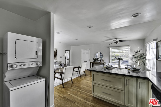 kitchen featuring stacked washing maching and dryer, dark wood-type flooring, stainless steel dishwasher, and ceiling fan