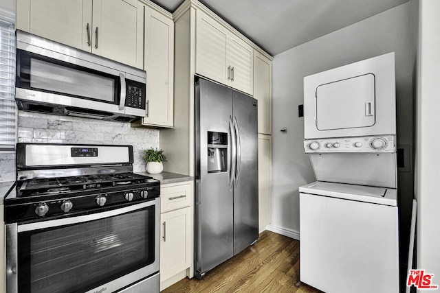 kitchen featuring stainless steel appliances, stacked washing maching and dryer, dark hardwood / wood-style flooring, and decorative backsplash