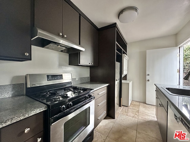 kitchen featuring light tile patterned flooring, stacked washer / drying machine, sink, and gas stove