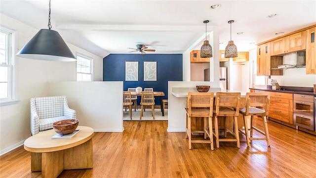 kitchen featuring pendant lighting, refrigerator, wall chimney exhaust hood, and light wood-type flooring