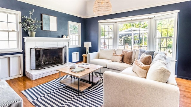 living room with a brick fireplace and light wood-type flooring