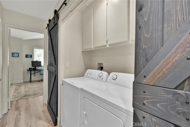 laundry room featuring cabinets, light hardwood / wood-style floors, a barn door, and washing machine and dryer