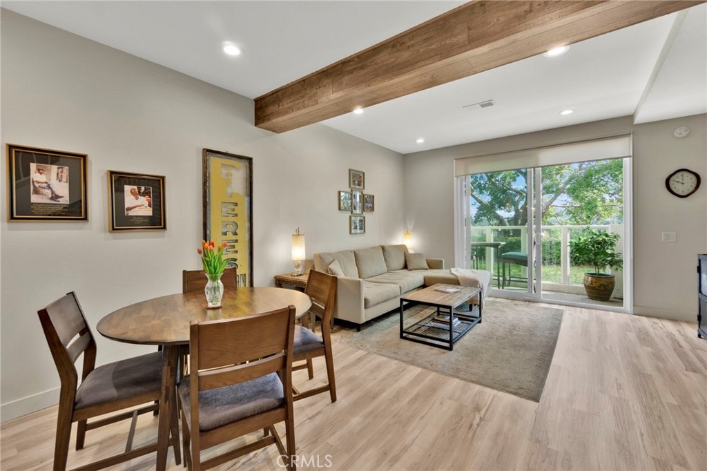 living room featuring beamed ceiling and light wood-type flooring