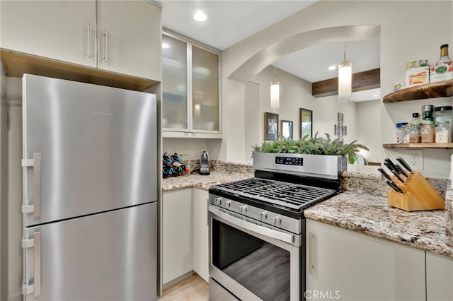 kitchen featuring pendant lighting, beamed ceiling, white cabinetry, stainless steel appliances, and light stone countertops