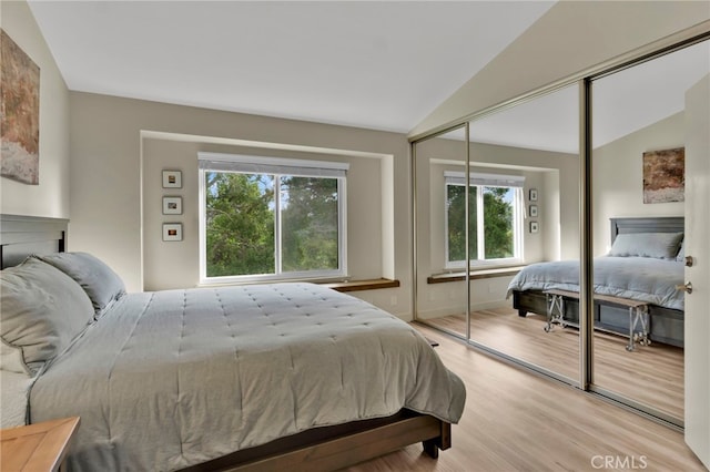 bedroom with lofted ceiling, a closet, and light wood-type flooring