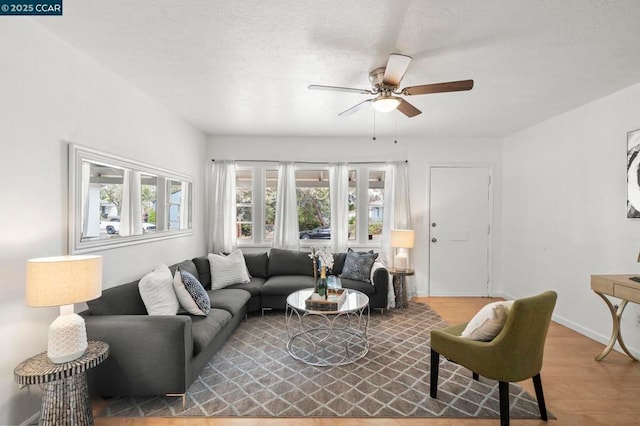 living room with a textured ceiling, light hardwood / wood-style floors, and ceiling fan