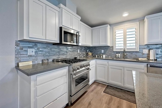 kitchen with white cabinetry, appliances with stainless steel finishes, sink, and light wood-type flooring