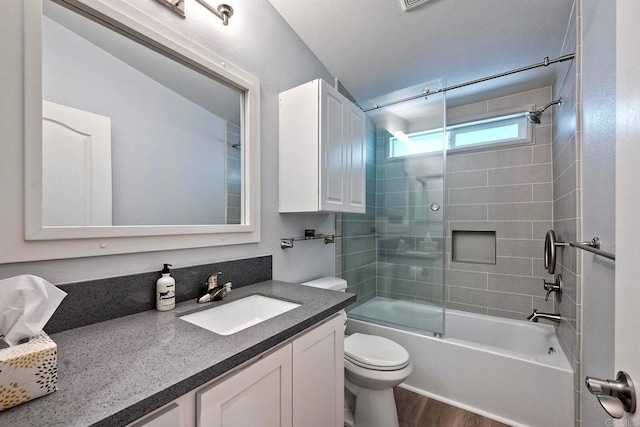 full bathroom with vanity, hardwood / wood-style flooring, shower / bath combination with glass door, and toilet