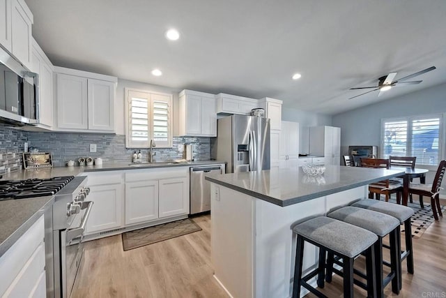 kitchen with sink, a kitchen island, white cabinets, and appliances with stainless steel finishes